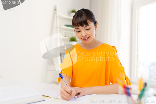 Image of happy student girl with book and notebook at home