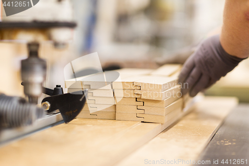 Image of close up of carpenter hand with boards at factory