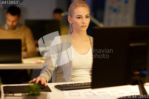 Image of businesswoman at computer working at night office