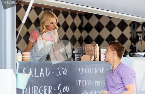 Image of saleswoman at food truck serving male customer