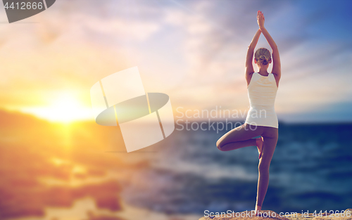 Image of happy woman making yoga tree pose over sea