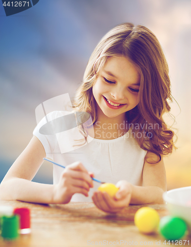 Image of happy girl coloring easter eggs