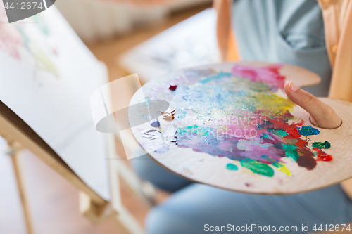 Image of artist with paint palette painting at art studio