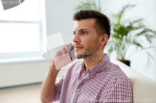 Image of smiling young man calling on smartphone at office
