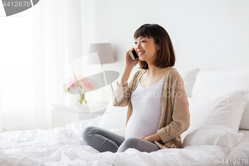 Image of happy pregnant woman calling on smartphone at home