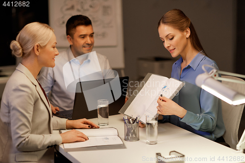 Image of business team with papers working at night office
