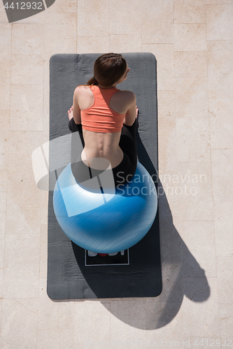 Image of woman doing exercise with pilates ball top view