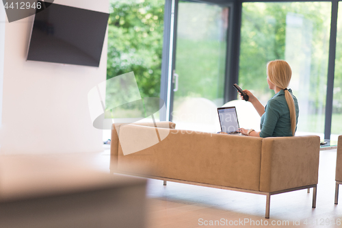 Image of Young woman using laptop at home