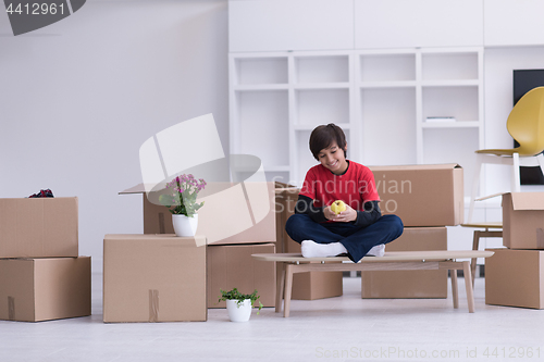 Image of boy sitting on the table with cardboard boxes around him