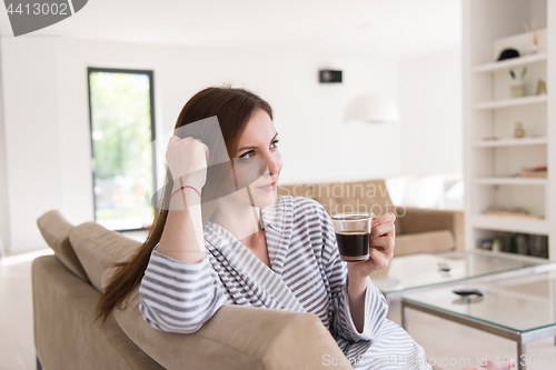 Image of young woman in a bathrobe enjoying morning coffee