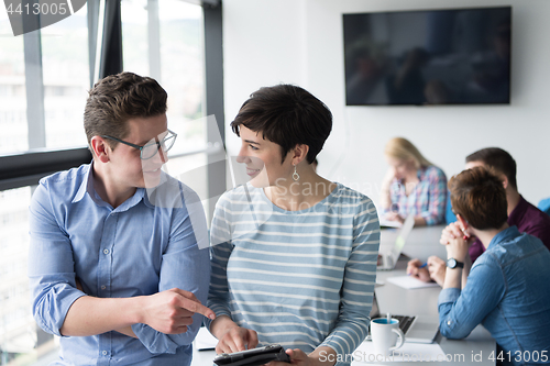 Image of Two Business People Working With Tablet in office