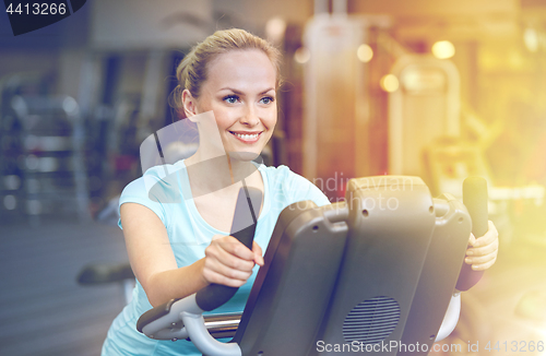 Image of smiling woman exercising on exercise bike in gym