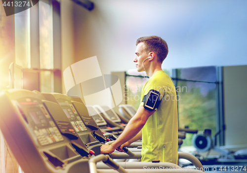 Image of man with smartphone exercising on treadmill in gym