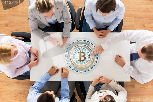 Image of business team at table with bitcoin icon