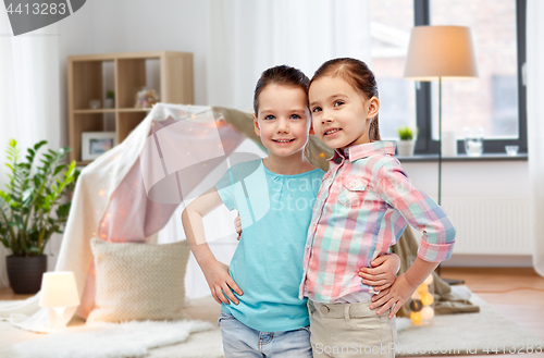 Image of happy smiling little girls hugging at home