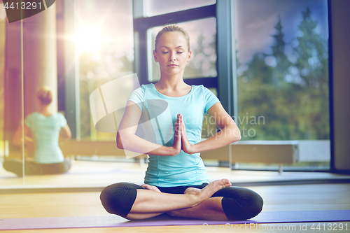 Image of happy woman meditating in lotus pose on mat