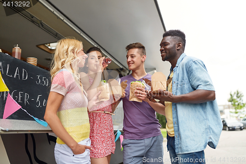 Image of happy friends with drinks eating at food truck