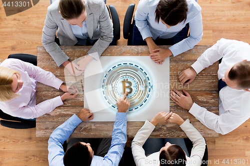 Image of business team at table with bitcoin icon