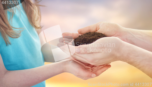 Image of close up of father and daughter hands holding soil