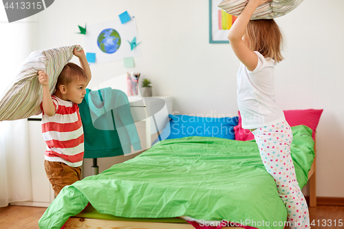 Image of kids playing and fighting by pillows at home