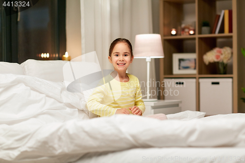 Image of happy little girl in bed at home at night