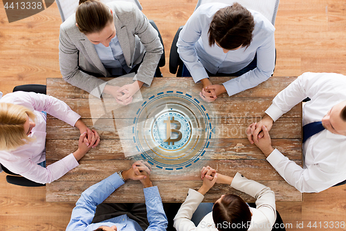 Image of business team at table with bitcoin icon