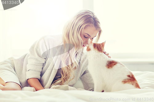 Image of happy young woman with cat in bed at home