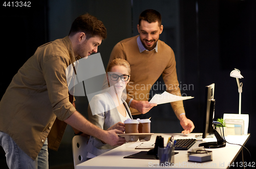 Image of business team with computer working late at office