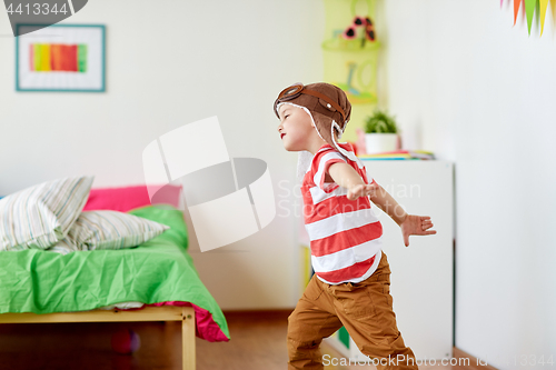 Image of happy little boy in pilot hat playing at home