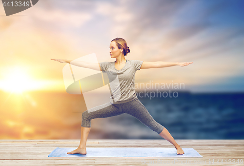 Image of woman making yoga warrior pose on mat