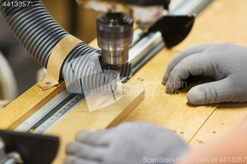 Image of carpenter with drill press and board at workshop