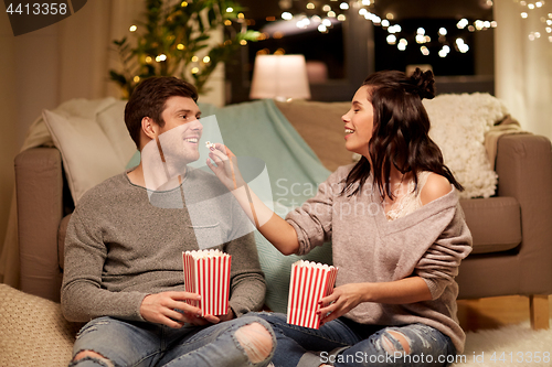 Image of happy couple eating popcorn at home