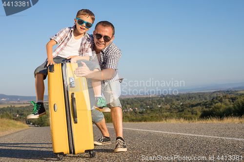 Image of Father and son standing in the park at the day time.