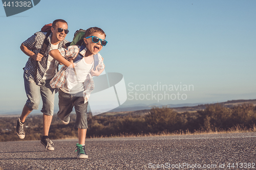 Image of Father and son running on the road at the day time.