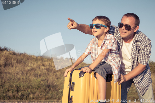 Image of Father and son standing in the park at the day time.