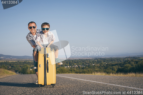 Image of Father and son standing in the park at the day time.