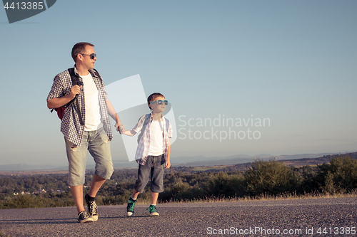 Image of Father and son standing in the park at the day time.