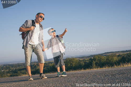 Image of Father and son standing in the park at the day time.