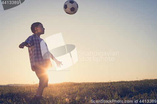 Image of Young little boy playing in the field  with soccer ball.