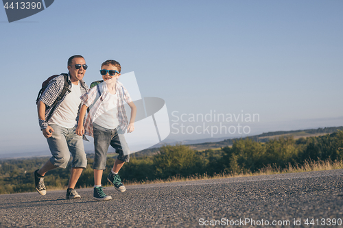 Image of Father and son running on the road at the day time.