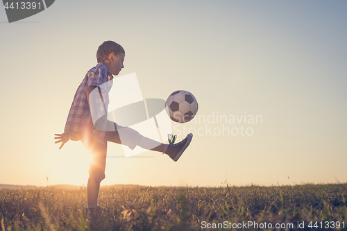 Image of Young little boy playing in the field  with soccer ball.