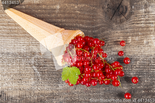 Image of Red currant fruits in ice cream cone on wooden table
