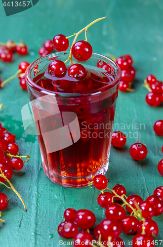 Image of Red currant juice in glass with fruits on wood table