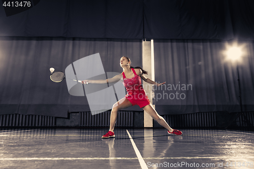 Image of Young woman playing badminton at gym