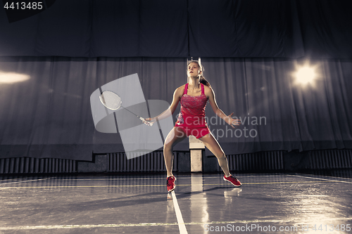 Image of Young woman playing badminton at gym