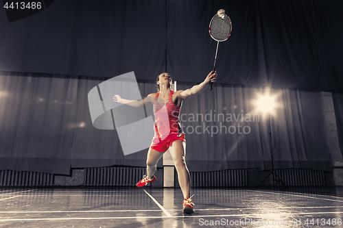 Image of Young woman playing badminton at gym