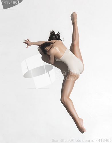 Image of Young beautiful dancer in beige dress dancing on gray background