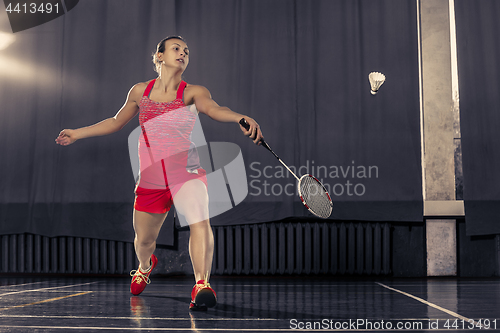 Image of Young woman playing badminton at gym