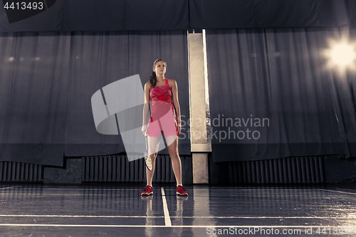 Image of Young woman playing badminton at gym