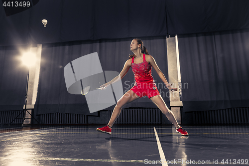 Image of Young woman playing badminton at gym